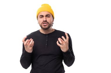 Öfkeli, 30 yaşında, sakallı, sıradan giyinmiş beyaz arka planda fotokopi çekilen kameraya bakan bir adam..