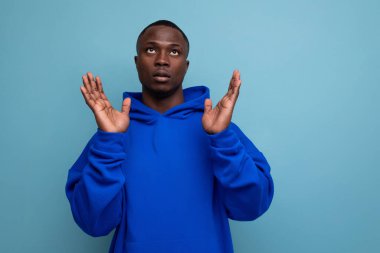 30 'lu yılların koyu tenli kapüşonlu tişörtlü Afrikalı' sının portresi. Stüdyo arka planında fotokopi aletiyle şüphe ve inkar duyguları olan..