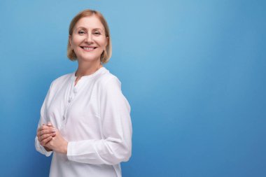 Güzel, sarışın, orta yaşlı, beyaz bluzlu, menopoz öncesi yaşlarında bir kadın..