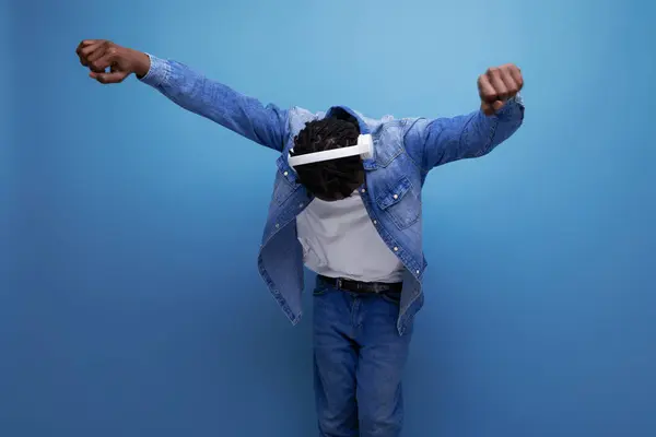 stock image energetic american man with dreadlocks in denim jacket dancing to music with headphones.