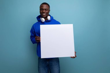 25 yaşındaki genç Amerikalı, arka planda fotokopi alanı olan bir reklam afişi gösteriyor..