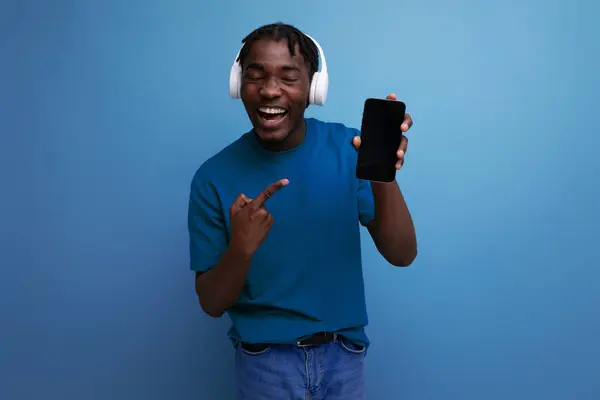 stock image positive young man listening to music using headphones and smartphone.