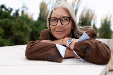 Başarılı, bakımlı, güzel, gri saçlı, sokakta şık bir takım elbise giymiş bir kadın emeklinin portresi..