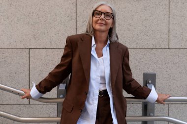 Başarılı, bakımlı, güzel, gri saçlı, şehirde dolaşan emekli bir kadının yakın çekimi..