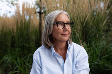 İş portresi. 60 yaşında, kahverengi ceketli, gri saçlı bir kadının başarılı portresi..