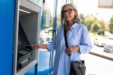 Orta yaşlı bir kadın ATM 'den para çekmek istiyor..