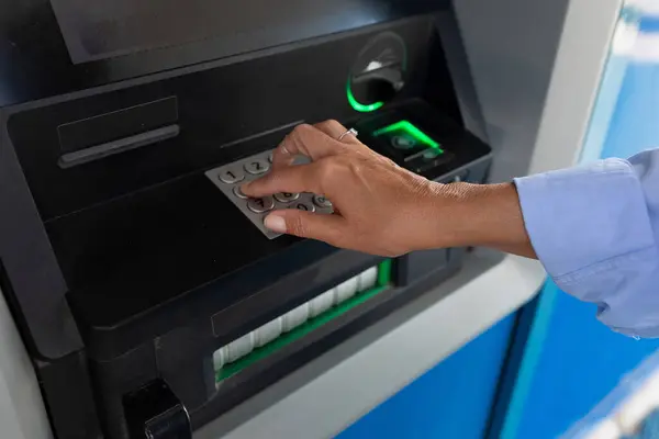 close-up of a woman entering a pin code at an ATM.