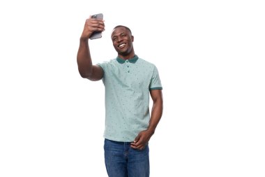 Tişört ve kot pantolon giymiş genç, narin bir Amerikalı telefonda selfie çekiyor..