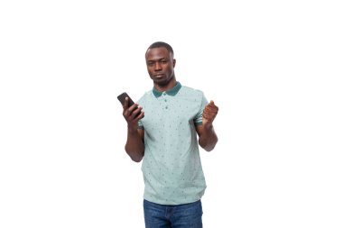 Genç Afrikalı sıradan giyinmiş bir adam, beyaz arka planda duran ve fotokopi alanı olan akıllı telefon kullanıyor..