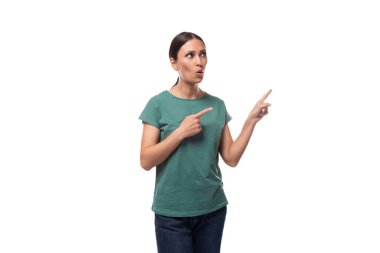 Basit bir tişört giymiş siyah saçlı genç bir kadın şaşkınlıkla elini yana gösteriyor..