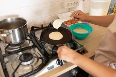 Kadın hamuru tavaya serer..