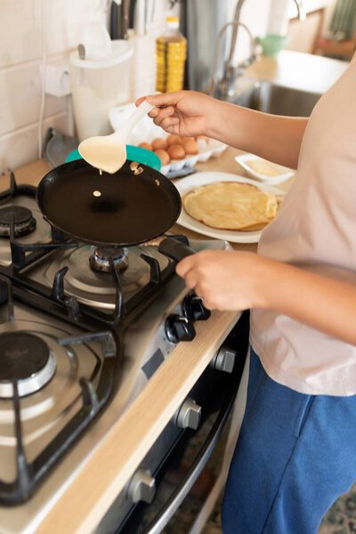 процесс приготовления блинов на сковородке, крупным планом на кухне.