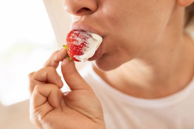 Genç kadın acıkıyor ve çilekten bir ısırık alıyor..