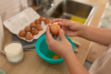 Kadın kahvaltı hazırlamak için yumurta kabuğu kırıyor..