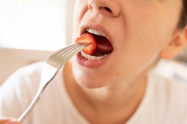 Kadın abur cubur yerken ağzına çilek koyar..