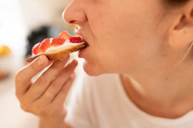 Çilek ve yoğurtlu tost yiyen bir kadın..