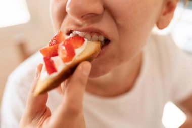 Genç bir kadın acıkıyor ve çilekli sandviç yemekten hoşlanıyor..