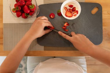 Kadınların elleri bir kavanoz ekşi kremaya çilek koyar..