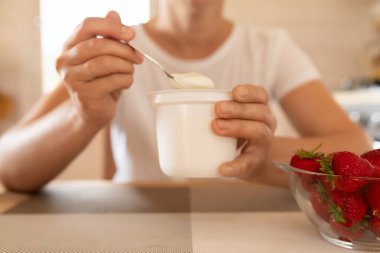 Bir kadın ekşi krema ve çilekten kahvaltı hazırlar..