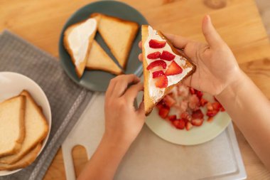 Çilekli krem peynirli tost yapan bir kadın..