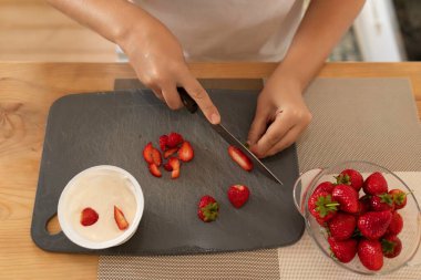 Bir kadının elleri çilekleri dilimlere ayırır..