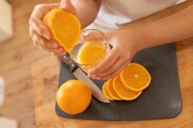 Bir kadının ellerinde sulu portakal dilimleri.