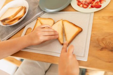 Kadın kızarmış ekmeği üçgen şeklinde dilimlemiş..