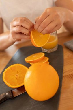 Bir kadının ellerinde sulu portakallar.