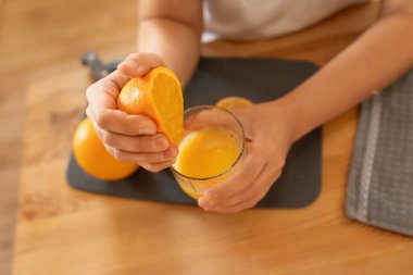 Bir kadının ellerinde sulu portakallar.