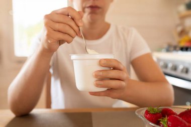 Bir kavanoz ekşi kremayı bir kadının ellerine ve yakınındaki çileklere sıkıştır..