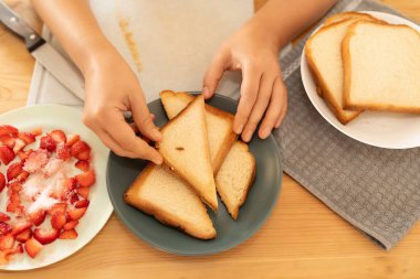 Kadın kızarmış ekmeği üçgen şeklinde dilimlemiş..