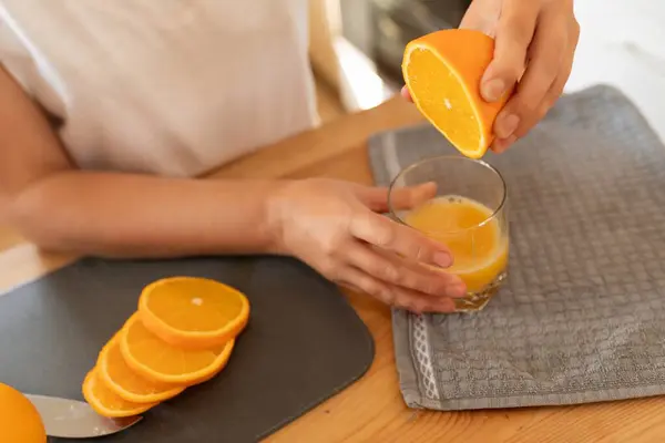 womens hands squeezing juice out of orange slices.