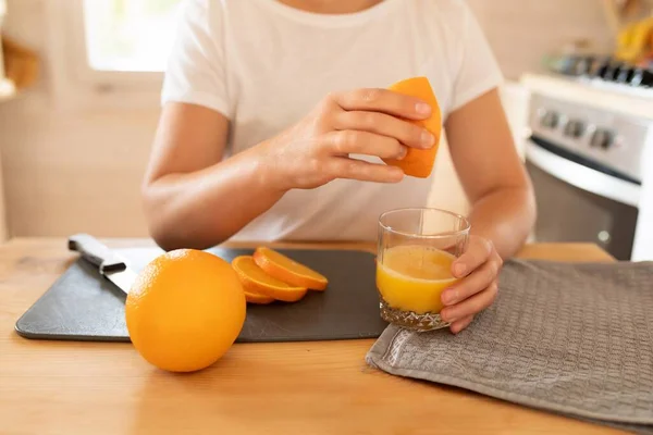 womens hands squeezing juice out of oranges..