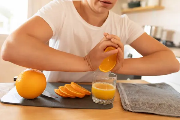 womens hands squeeze an orange for juice.