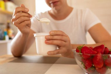 Kadınların elleri bir kaşıkla kavanozdan ekşi krema çıkarıyor..