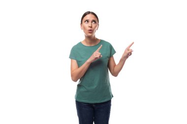 Genç, karizmatik, siyah saçlı, saçları toplanmış bir kadın. Basit bir tişört ve kot pantolon giymiş. Parmağını işaret ediyor..