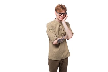 Bej gömlekli, kızıl saçlı yakışıklı bir adam beyaz arka planda gözlük takıyor..