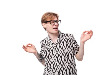 Gözlüklü, kolunda dövmesi olan genç, kızıl saçlı bir adamın yan tarafına bakarken..