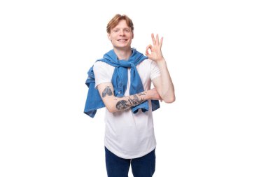 Genç, başarılı, beyaz, kısa kızıl saçlı, mavi tişörtlü, beyaz tişörtlü bir adam..