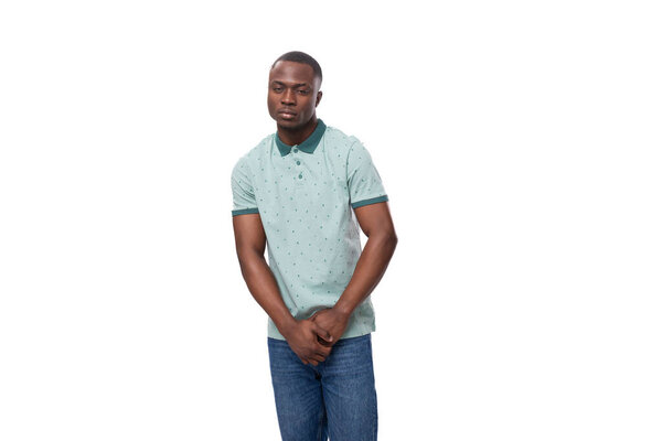 Young charming american guy dressed in a mint t-shirt and jeans on a white background with copy space.
