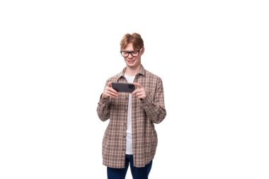 Gözlüklü yakışıklı beyaz çocuk telefonda oyun oynuyor..