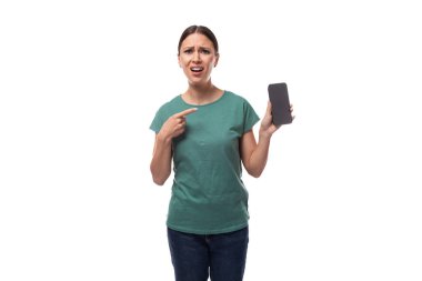 Genç, karizmatik, siyah saçlı, saçları toplanmış bir kadın, basit bir tişört ve kot pantolon giyip parmağını akıllı telefon ekranına gösteriyor..