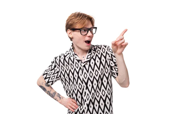 Kızıl saçlı, kollarında dövmesi olan genç ve duygusal bir adam kısa kollu bir gömlek giyip yüzünü buruşturuyor..