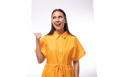 Parlak sarı kısa kollu bir elbise giymiş güzel esmer kadın dikkat çekiyor ve haberleri anlatmak istiyor..