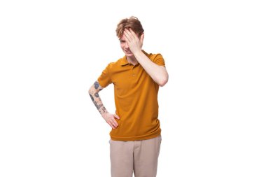 Yazlık tişört giymiş kısa kızıl saçlı genç bir adamın kafası karışıyor..