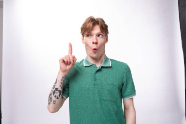 Yeşil tişört giymiş, kızıl saçlı, genç, beyaz bir adam, arka planda fotokopi alanı olan bir fikirden esinlenmiştir..