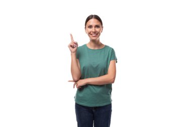 Yeşil, basit bir tişört giymiş, kendine güvenen genç, narin bir kadın. Makyajlı tişört, elini reklama doğru uzatıyor..