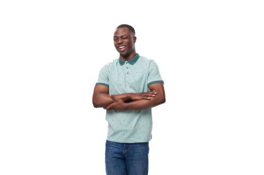 Tişört ve kot giyen utangaç Afrikalı genç adam düşünceli bir şekilde duruyor..