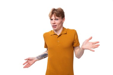 Yazlık tişört giymiş kısa kızıl saçlı genç bir adamın kafası karışıyor..