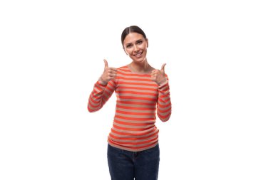 Çizgili turuncu ceket ve kot pantolon giymiş, ince, esmer, gülümseyen bir kadın..